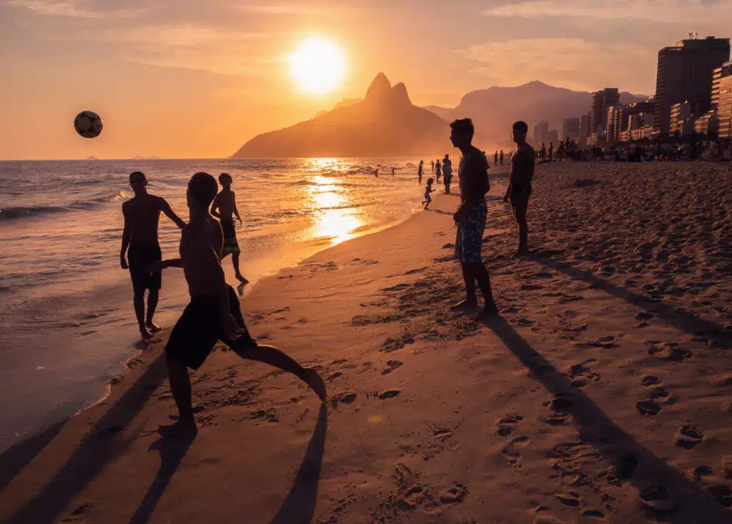 Dennis Hernandez goes to Brazil. People playing on the beach during a sunset